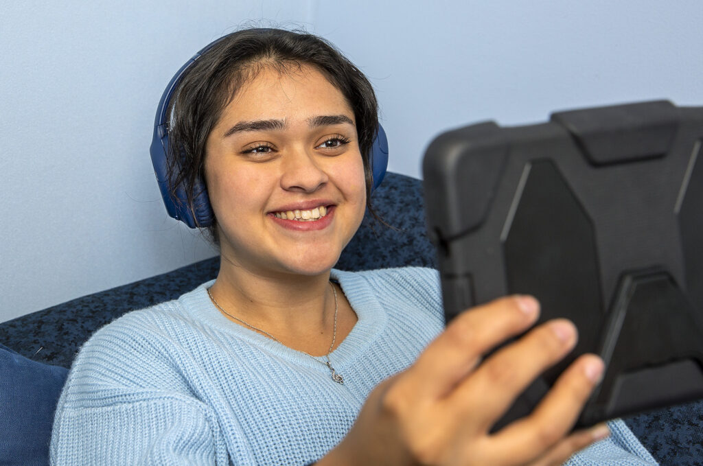 woman streaming media on tablet with library card