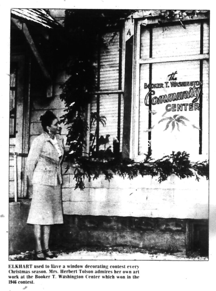 Ruth Tolson standing outside The Booker T. Washington Community Center, decorated for Christmas. The center won the city's window-decorating competition in 1946.