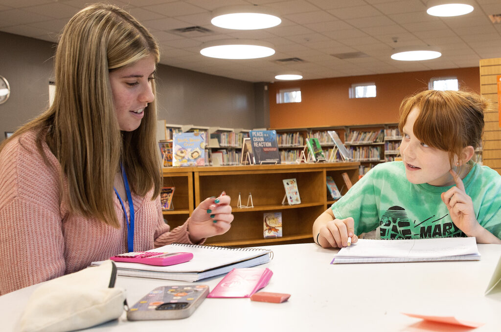 A student receives help with homework from a mentor in the Elkhart Public Library