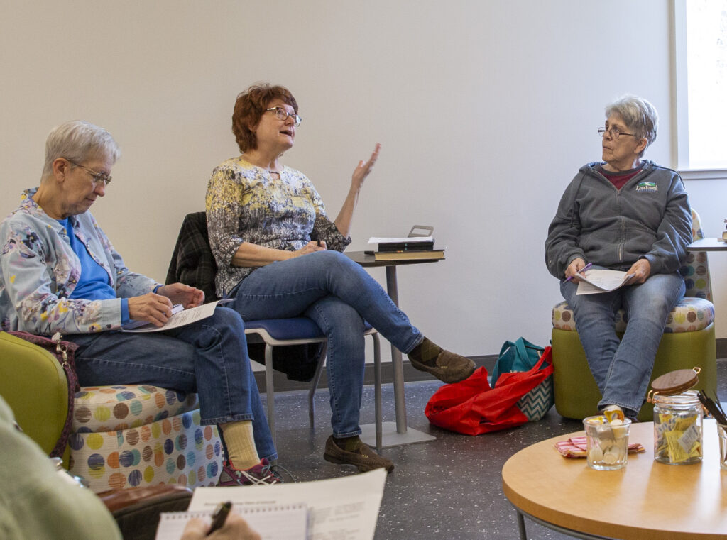 A group of women participate in a book discussion group at the library.
