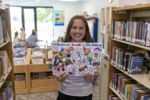 Girl holding Summer Reading Gameboard. Gameboards and rewards motivate kids to read.